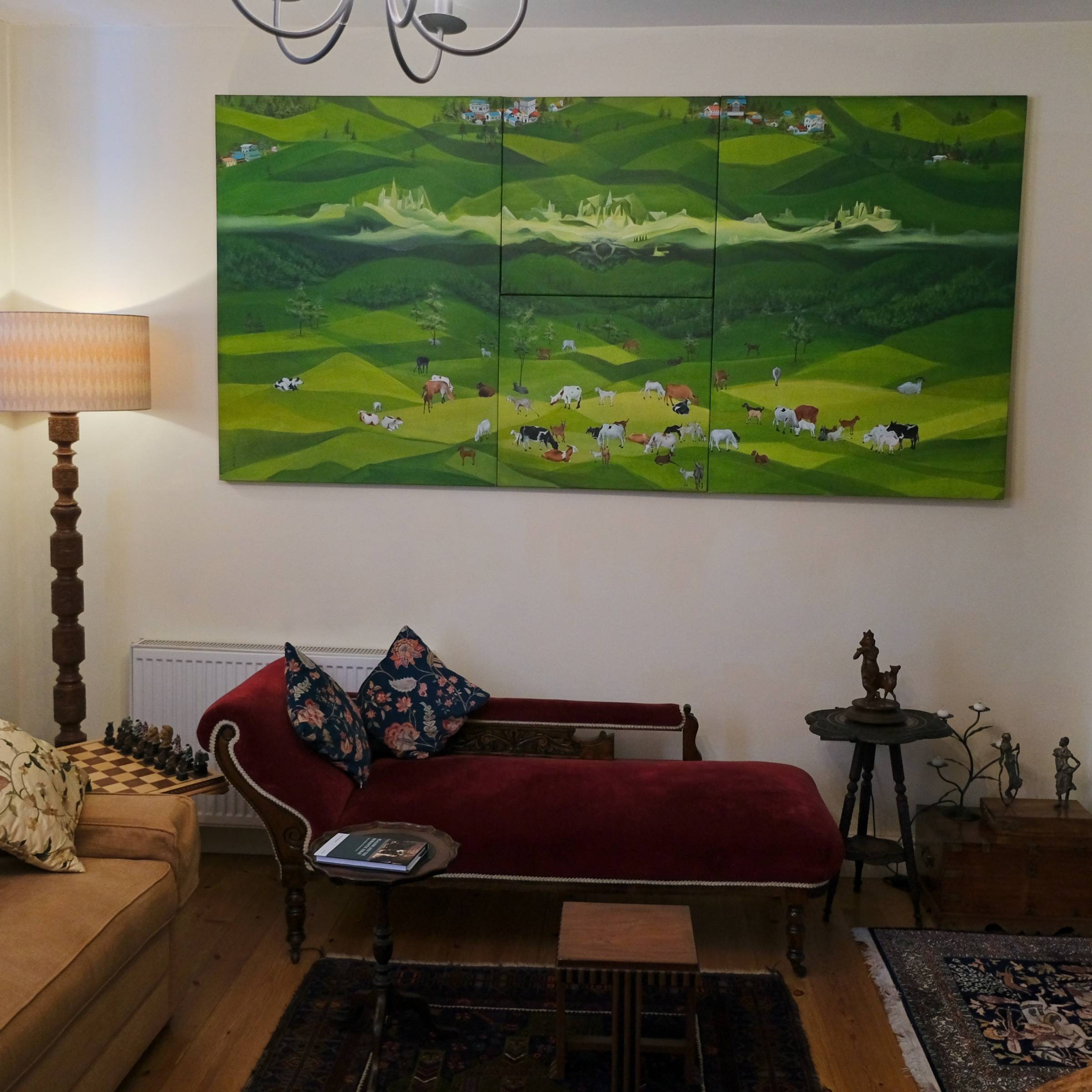 The sitting room, with a large green landscape painting above a red sofa