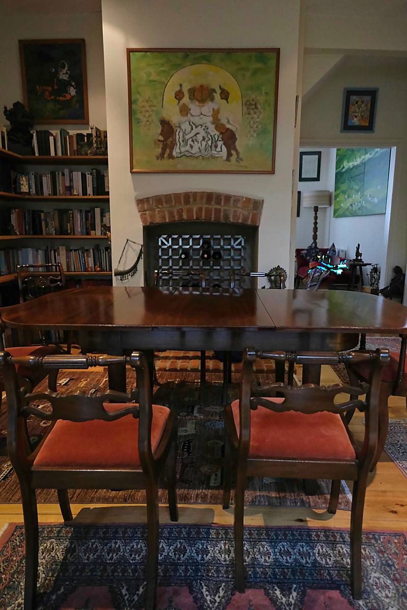 Dining chairs in front of a bookcase and a framed painting