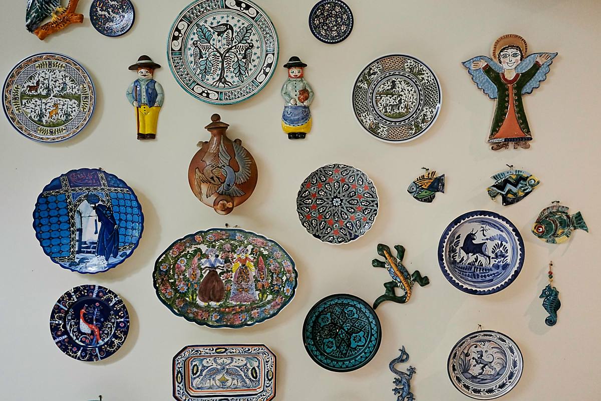 A wall of painted plates, ceramic angels and small figures