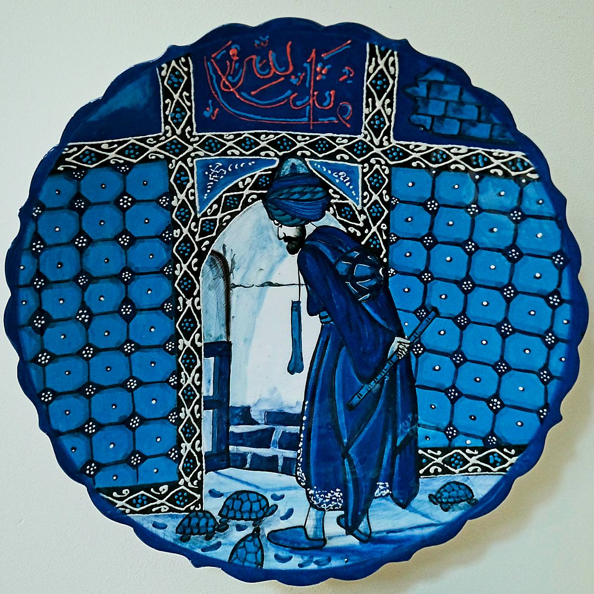A blue and white painted plate with a standing figure in a doorway