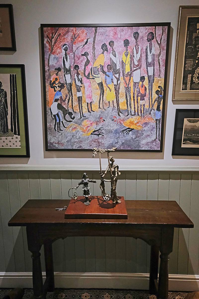 A dark wooden table with bronze figures below a painting